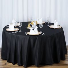 the table is set with black linens and gold place settings for two people to sit at