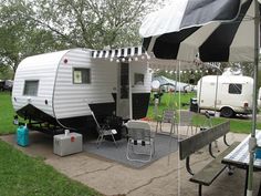 an rv is parked on the side of the road near picnic tables and umbrellas