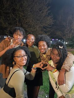 a group of young women standing next to each other in front of a park at night