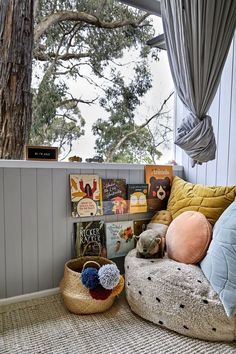 a bed with pillows and books on top of it next to a window in a room