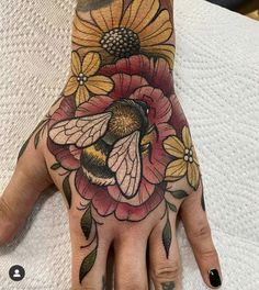 a woman's hand with a bee and flower tattoo on the middle of it