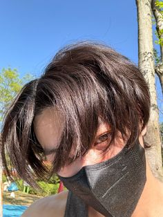 a woman wearing a neck gaiter with trees in the background