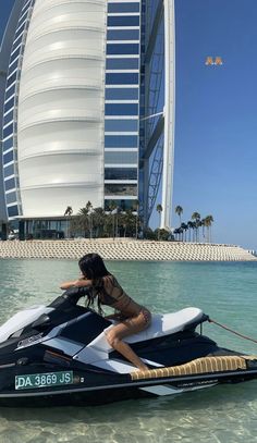 a woman riding on the back of a jet ski in front of a tall building