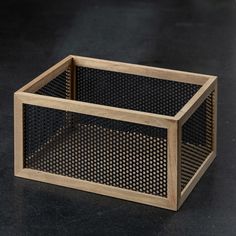 a wooden box sitting on top of a black table next to a white object with holes in it