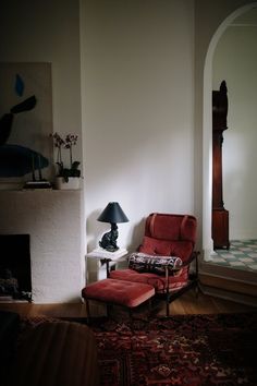 a living room with a red chair next to a fireplace