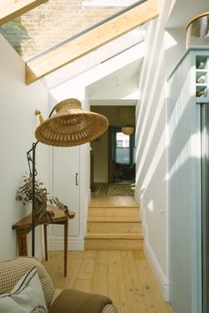 a room with wooden flooring and a skylight in the ceiling, along with a wicker hat hanging from the ceiling