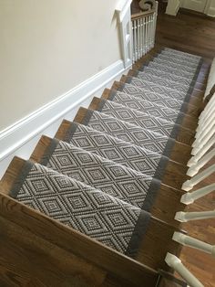 the stairs are made of wood and have gray rugs on them, along with white handrails