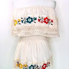 100% Artisanal Garment - Made In Mexico. Finely Embroidered Dress Made By The Artisans From Puebla. Embroidered Flowers In The Front. Flowy And Frilly, With Lace Layers On The Borders. The Waist Of The Dress Has Elastic, Which Adapts To Your Body Shape. This Is An Artisan Piece, Each Of These Dresses Is Unique So There May Be Slight Variations In The Colors Of The Flowers. This Type Of Dress Requires The Talent Of Many Artisans Who Share A Passion For Mexican Culture. Add A Touch Of Fiesta And V White Peasant Embroidered Dress, Bohemian Cotton Embroidered Dress With Lace Trim, Bohemian Embroidered Cotton Dress With Lace Trim, White Peasant Dress With Embroidered Hem, Folk Style Beige Dress With Floral Embroidery, White Peasant Dress With Embroidered Border, Bohemian Cream Dress With Floral Embroidery, White Folk Style Embroidered Dress, Bohemian Cream Dress With Intricate Embroidery