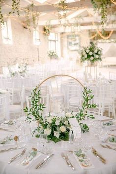 a table set up with white flowers and greenery