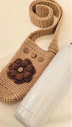 a crocheted bag with a flower on it and a water bottle next to it