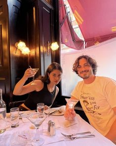 two people sitting at a table with wine glasses