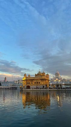 the golden building is reflected in the water at sunset or dawn with blue sky and clouds