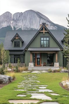 a green house with stone steps leading up to the front door and large mountains in the background