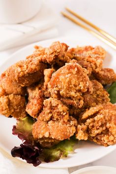 fried food sitting on top of a white plate next to chopsticks and sauce