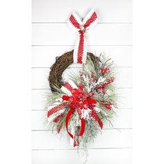 a christmas wreath hanging on the side of a white wall with red and white decorations