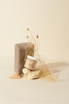 a bottle of cream sitting on top of a pile of sand next to a rock