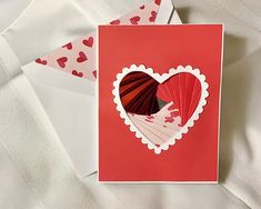 a red heart shaped card on top of two envelopes