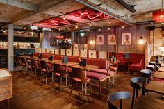 an empty restaurant with wooden tables and red upholstered chairs, wood flooring and exposed lighting