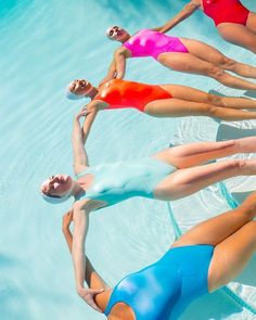 four women in swimsuits are floating in a pool together, with their backs turned to the camera