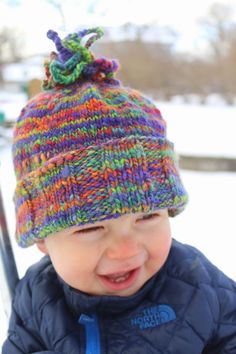 a small child wearing a knitted hat in the snow