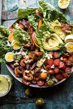 a salad with shrimp, lettuce, tomatoes, avocado and dressing