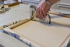 a person using a pair of scissors to cut out some fabric on a table top