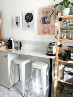 two white stools in front of a counter with coffee maker and cups on it