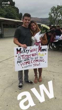 a man and woman standing next to each other holding a sign