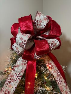 a red and white bow on top of a christmas tree