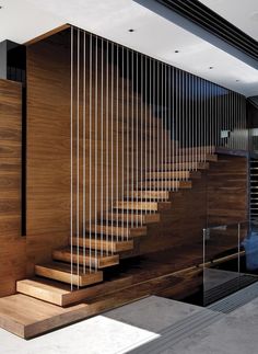 there is a wooden stair case next to the glass wall in this modern house,