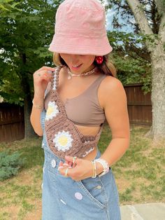 a woman wearing a pink hat and holding a crochet flower in her pocket