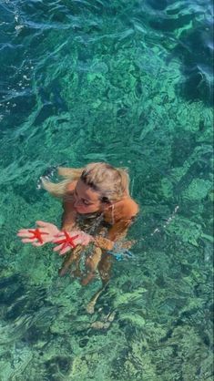 a woman swimming in the ocean with her hand out to touch the water's surface