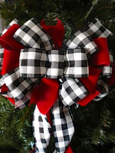 a black and white checkered bow hanging on a christmas tree with red ribbon around it