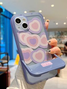 a woman holding up her phone case with hearts on the front and back cover in purple