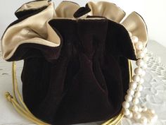 a brown velvet purse with gold trim and pearls on a lace doily tablecloth