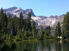 a lake surrounded by trees with mountains in the background