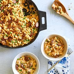 two bowls of macaroni and cheese on a table with spoons next to it