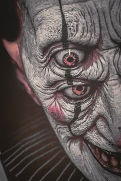 an evil clown with red eyes and white makeup