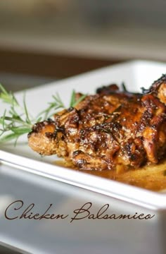 a white plate topped with meat covered in sauce and garnished with green herbs