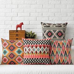 colorful pillows on a white couch in front of a brick wall