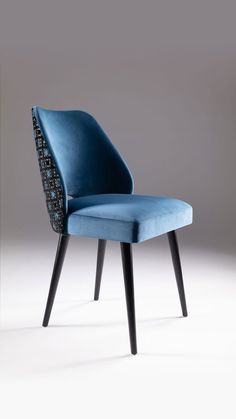 a blue upholstered chair with black legs and an intricate design on the back