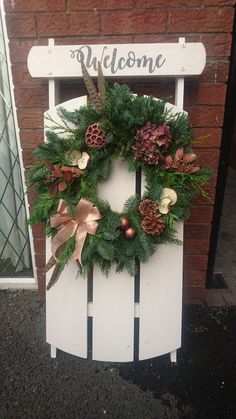 a white wooden chair with a wreath on it's back and welcome sign above the door