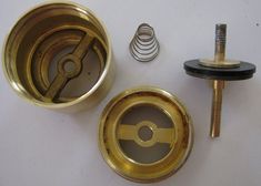 an assortment of brass parts and screws on a white surface