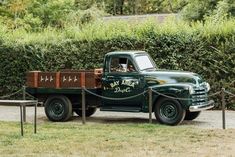 a green truck parked in front of a bush