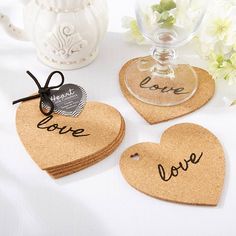 three cork coasters with the words love and two hearts attached to them, sitting on a table