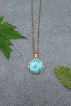 "Introducing this new crystal to my shop, none other than this natural beauty Larimar! Absolutely beautiful stone resembling gentle sea ripples The listing is not for the exact stone in the photo but very similar. The pictured version has been sold. This stone comes in a 20mm size, round and polished on a gold stainless steel pendant. This pendant comes on a stainless steel curb chain of 2mm in width on a custom length. Larimar is also known as \"Stefilia's Stone\", it has a unique blue variety Elegant Amazonite Necklace For Gift, Elegant Round Amazonite Necklace, Hypoallergenic Amazonite Jewelry As Gift, Handmade Round Larimar Necklaces, Handmade Larimar Round Necklace, Hypoallergenic Larimar Jewelry As A Gift, Hypoallergenic Larimar Jewelry For Gifts, Round Larimar Jewelry For Gifts, Round Larimar Jewelry Gift