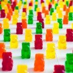 many gummy bears are arranged in rows on a white tablecloth with red, green, yellow and orange squares