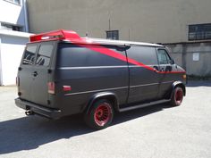 an old van with red stripes parked in a parking lot next to a garage door