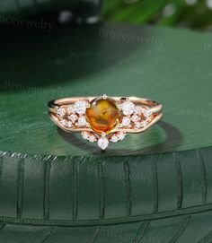 a close up of a ring with an orange stone and diamonds on it's side