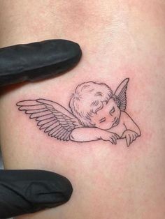 a small angel tattoo on the thigh